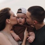 A heartwarming family moment captured during sunset with parents and toddler outdoors.